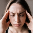 Woman experiencing migraine without aura with intense head pain and temple pressure