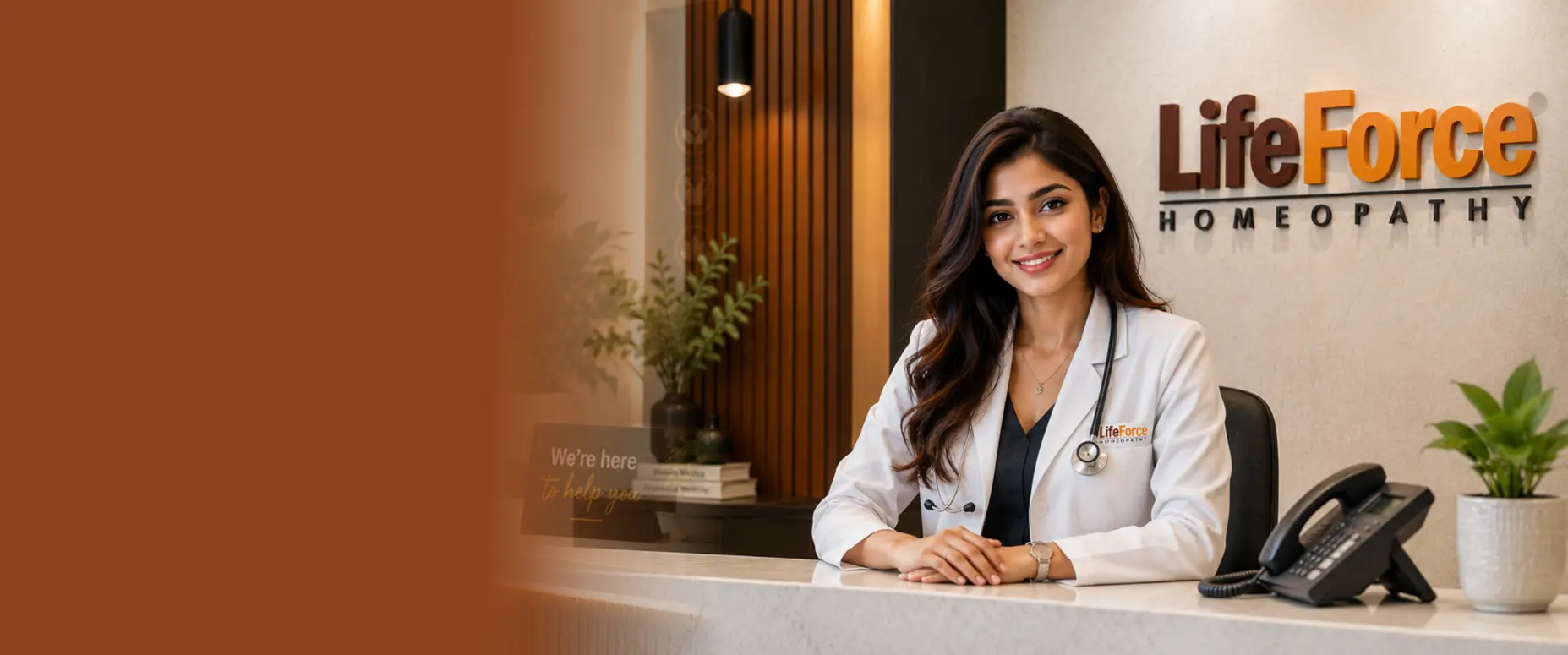 Smiling homeopathic doctor at the Life Force Homeopathy reception desk wearing a white coat and stethoscope, welcoming patients for consultations and appointments.